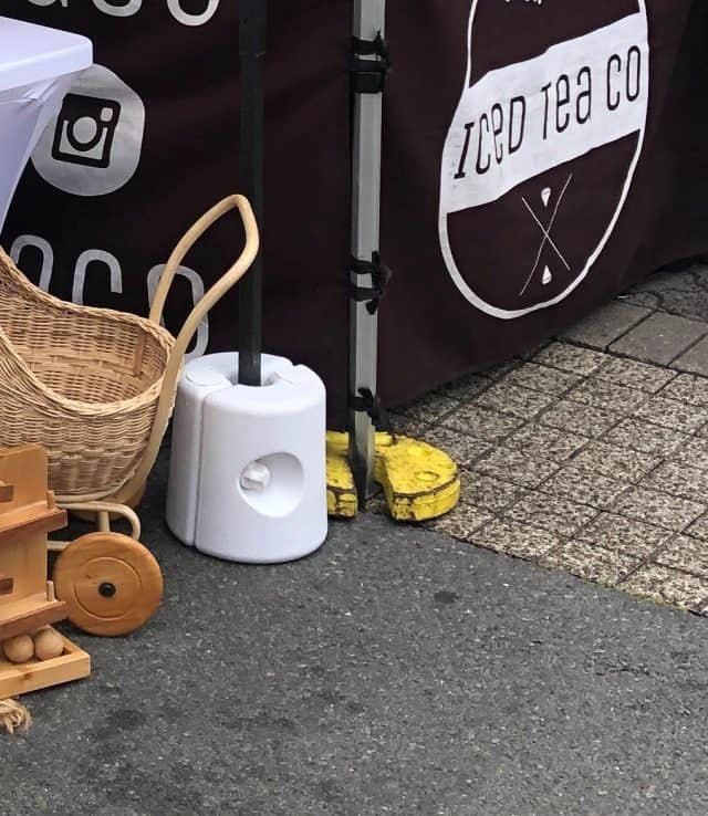 How Much Weight to Hold Down a 10x10 Canopy - photo of weight drum and weight  plate used to hold down a canopy at a market place